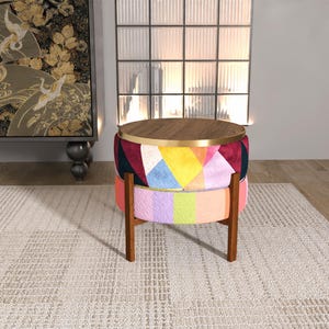 May include: A round, colorful accent table with a wooden top and geometric patchwork design. The table has a dark wood frame and a rainbow-colored lower section. The top is a warm brown color with a gold trim.