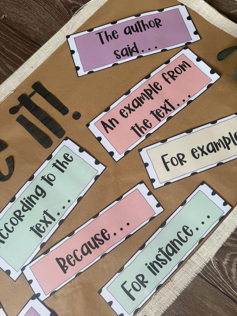 May include: A brown poster board with colorful rectangular labels. The labels have black polka dot borders and text such as "The author said...", "An example from the text...", and "Because...". The poster board is decorated with black lettering.