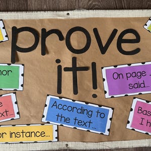 May include: A brown poster with the words "prove it!" in large black letters. Surrounding the text are colorful rectangles with phrases like "For example..." and "According to the text..." in black text.