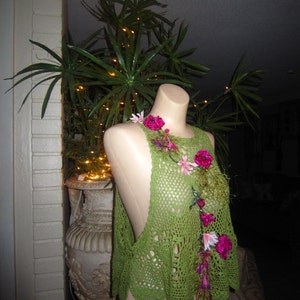 May include: Green crochet top with pink and green floral embellishments. The top is sleeveless and has a loose, flowing fit.