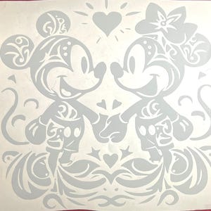 Puede incluir: Una calcomanía gris claro con Mickey y Minnie Mouse tomados de la mano, con patrones decorativos. Un corazón y un diseño de sol están encima de ellos. Los personajes sonríen y el diseño general es romántico y caprichoso.