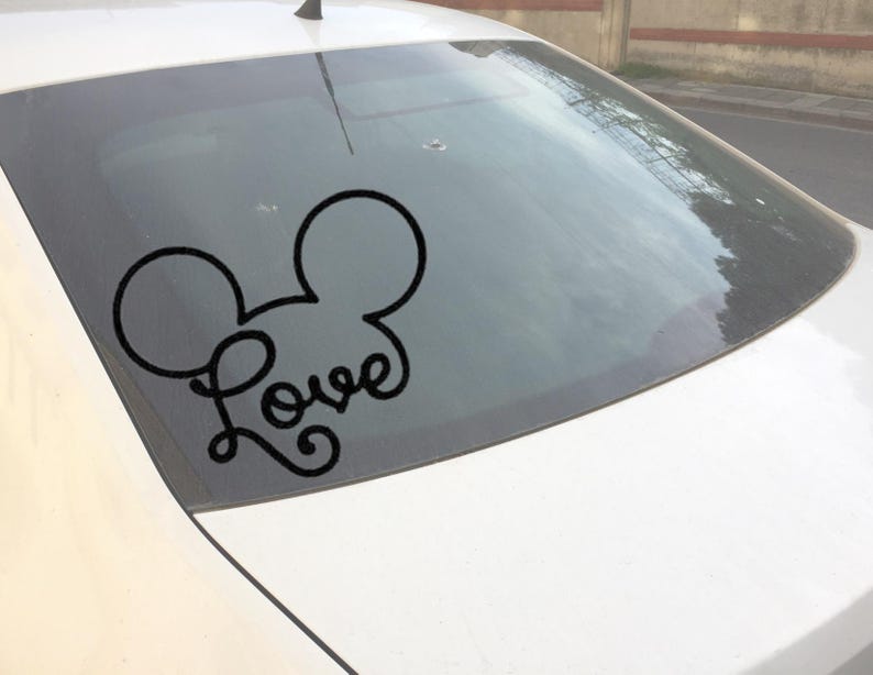 Puede incluir: Calcoman&iacute;a de vinilo negro con las orejas de Mickey Mouse y la palabra "Love" en cursiva. La calcoman&iacute;a est&aacute; aplicada en la ventana trasera de un coche blanco. Un dise&ntilde;o popular para accesorios de coche.