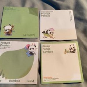 Peut inclure: Ensemble de quatre blocs de notes autocollantes sur le thème du panda avec différents motifs. Les blocs présentent des illustrations de pandas avec différentes activités, comme jouer de la guitare, lire un livre et s'asseoir dans une forêt de bambous. Le texte "Protect Pandas" apparaît sur deux des blocs.