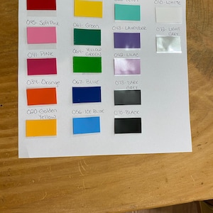 May include: A color chart featuring rectangular swatches in various hues, including red, yellow, green, blue, pink, and grey. Each swatch is labeled with a number and color name, such as "031- RED" and "070- BLACK".