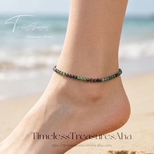 May include: Ankle bracelet made of small, round green and red beads. The jewelry is worn on an ankle, with a sandy beach in the background. The text "Timeless Treasures" and "TimelessTreasuresAha" are visible.
