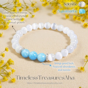 May include: A white Selenite and Aquamarine beaded bracelet. The bracelet features white and light blue beads, with silver-colored accents. The image includes text that says "clear negative energy, cleanse other crystals, and facilitate spiritual growth."