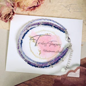 May include: A multi-strand bracelet featuring blue, purple and white beads. The bracelet has a silver clasp and a heart charm.