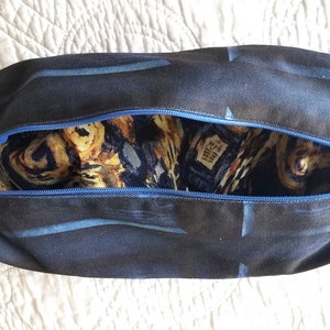 May include: A blue zippered pouch with a black and blue starry night print on the outside and a yellow and blue starry night print on the inside.