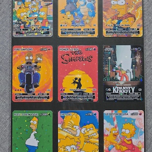 May include: Nine collectible trading cards featuring characters from The Simpsons animated series. The cards display various characters like Bart, Homer, and Lisa in colourful illustrations. The cards are arranged in a black display sheet.