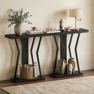 May include: A long black console table featuring a flat rectangular top and a base with angled metal supports. The table includes a lower shelf for storage, with a woven basket on one side and two ceramic vases on the other side of the base.