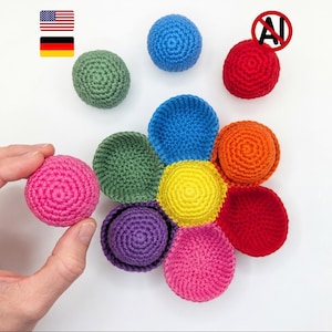 Könnte beinhalten: Eine Sammlung farbenfroher, handgehäkelter Bälle und Schalen in verschiedenen Farbtönen, darunter Rosa, Grün, Blau, Gelb, Orange, Rot und Lila. Die Bälle sind rund, die Schalen schalenförmig. Das Bild ist vor einem weißen Hintergrund.