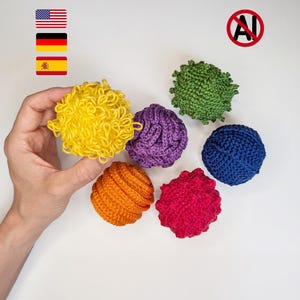 Può includere: Una collezione di sei oggetti sferici all'uncinetto in vari colori e texture. Il set include una palla gialla con anelli, una palla verde testurizzata, una palla viola simile a un cervello, una palla blu, una arancione e una palla rossa bitorzoluta.