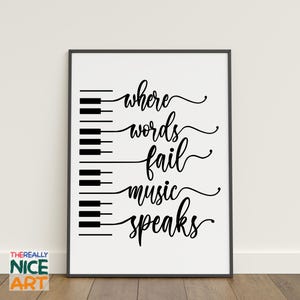 May include: Framed art print with a white background and black text that reads "where words fail music speaks." The design includes a piano keyboard graphic. The artwork is in a black frame.