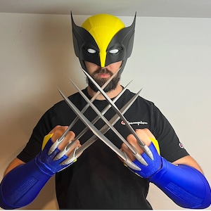 May include: A person wearing a yellow and black Wolverine mask and blue gloves with silver claws. The claws are extended and crossed in front of the person.