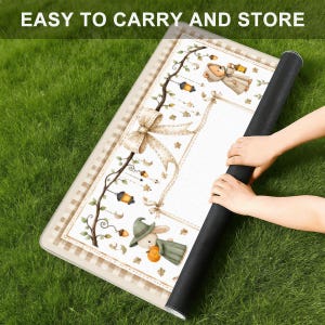 May include: A rectangular mat with a white center featuring a brown checkered border and illustrations of a bear in a hooded cloak and a rabbit in a green hat holding a pumpkin, accented by hanging lanterns, stars, and a large beige bow.