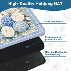 Op de afbeelding: Hoogwaardige Mahjong-mat met een bloemenontwerp met blauwe hortensia's en witte rozen. De mat heeft een zacht technisch stoffen oppervlak, milieubescherming XPE en een antislip dikke rubberen schuimrug.