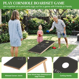 May include: A cornhole board set featuring a black surface with white text reading ASHLEY & MICHAEL and the date 06.23.26. The set includes pine wood legs, waterproof edge frames, mitered corner joints, and red and blue bean bags for tossing.
