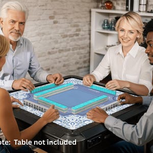 May include: A group of four people playing Mahjong. The game set features blue and white tiles, a blue playing surface, and a decorative patterned mat. The game is set on a black table. The text "Note: Table not included" is visible.