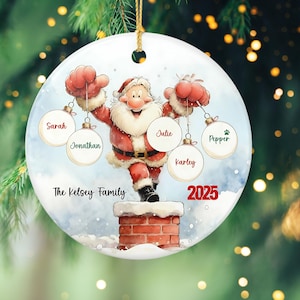 May include: A round Christmas ornament featuring Santa Claus on a chimney, holding ornaments with names. The ornament has the text "The Kelsey Family" and the year "2025". The ornament is white with a gold string.