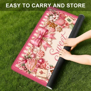 May include: A rectangular pink mat with a candy-themed design, featuring a large pink bow, candies, and the word "Sweet." The mat is rolled up, with the text "EASY TO CARRY AND STORE" at the top.