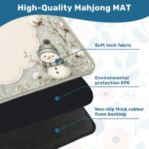 May include: A Mahjong mat featuring a snowman illustration on a light blue background with cotton sprigs. The mat consists of three layers: a soft tech fabric top, an environmental protection XPE middle layer, and a non-slip thick rubber foam backing.