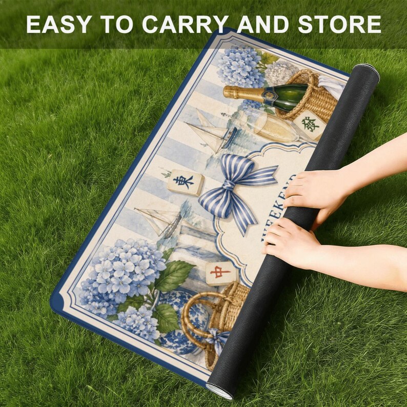 May include: A rolled-up picnic mat with a nautical design featuring sailboats, blue hydrangeas, and a striped bow. The mat has a blue border and the text "EASY TO CARRY AND STORE".