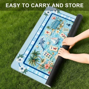 Puede incluir: Una alfombra azul enrollada con un tema de Florida, con un delf&iacute;n, un velero, palmeras y detalles florales. La alfombra tiene el texto "WELCOME TO FLORIDA" y "EASY TO CARRY AND STORE".