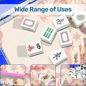 May include: White Mahjong tiles with blue edges and various symbols in red, green, and black are scattered on a floral patterned surface. The text "Wide Range of Uses" is at the top. The image also includes dominoes and playing cards.