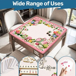May include: A square game table mat featuring a pink scalloped border and a central print of summer-themed items including pink hydrangeas, striped umbrellas, citrus slices, sunglasses, and mahjong tiles on a light cream background.