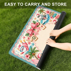 May include: A rolled-up, rectangular mat with a colorful, festive design featuring Santa Claus, palm trees, and a large pink bow. The mat has a teal border and the text "EASY TO CARRY AND STORE" at the top.
