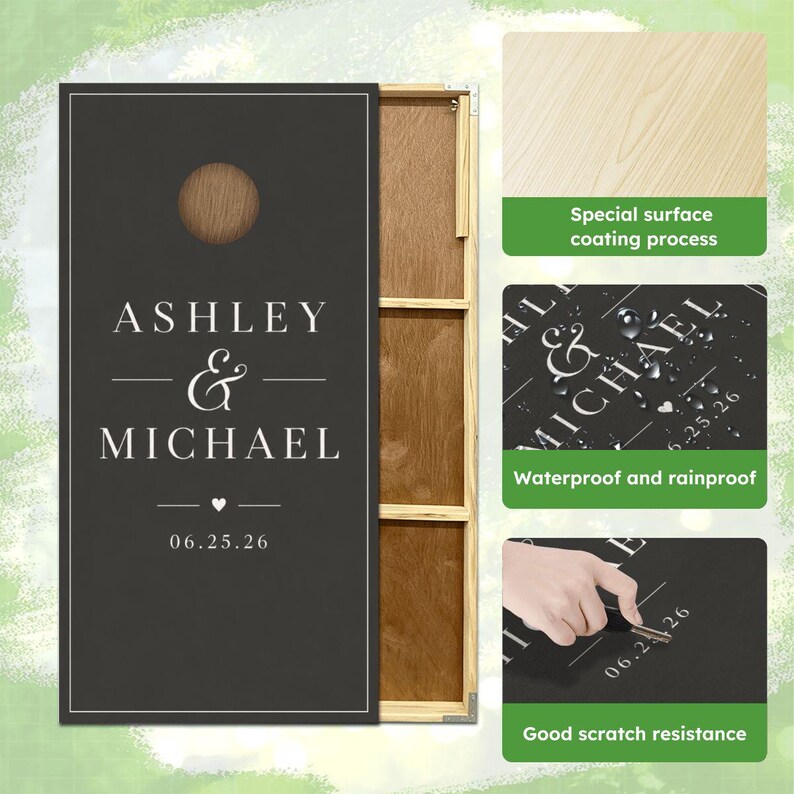 May include: A rectangular wooden cornhole board with a dark gray surface, featuring the white text ASHLEY & MICHAEL and the date 06.25.26. The board has a circular hole at the top and a natural wood frame visible on the side.