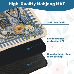 May include: A high-quality Mahjong mat with a blue and white floral design, a bagel, and a pigeon. The mat has a soft tech fabric, environmental protection XPE, and a non-slip thick rubber foam backing. The text "High-Quality Mahjong MAT" is at the top.