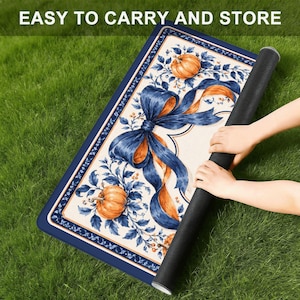 May include: A rectangular mat featuring a cream-colored center with a large blue ribbon bow, orange pumpkins, and blue foliage. The border is dark blue with a thin orange line. The text EASY TO CARRY AND STORE is printed at the top.
