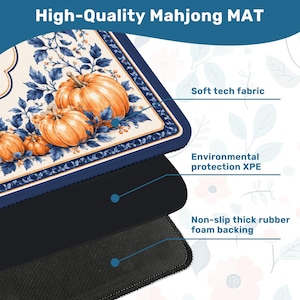 May include: A rectangular Mahjong mat featuring a cream-colored surface with orange pumpkins and blue foliage. The mat is composed of three layers: a soft tech fabric top, an environmental protection XPE middle layer, and a non-slip thick rubber foam backing.