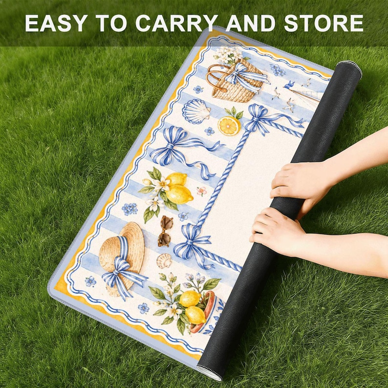 Pu&ograve; includere: Un tappeto rettangolare arrotolato con un design costiero con limoni, un cappello di paglia e fiocchi blu. Il tappeto ha un bordo a righe blu e bianche e il testo "EASY TO CARRY AND STORE" in alto.