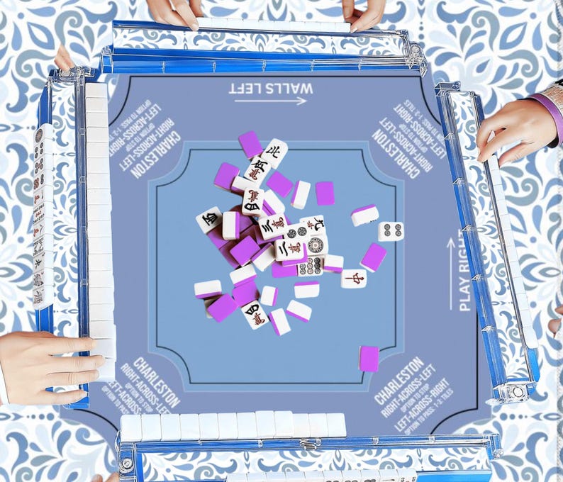 May include: A light blue Mahjong game set with white and purple tiles. The game board has text that reads "Walls Left" and "Play Right". The game is set on a patterned surface, with hands visible around the board.