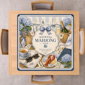 May include: A square wooden table with a blue and white Weekend Mahjong Club design. The design includes a bow, flowers, sailboats, and various Mahjong game elements. The table is surrounded by four wooden chairs.