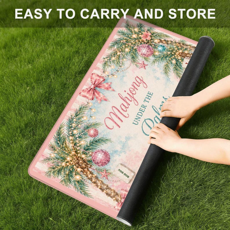May include: A pink and white Mahjong mat with a palm tree design, Christmas lights, and the text "Mahjong Under the Palms." The mat is rolled up, showing a black underside. The text "EASY TO CARRY AND STORE" is at the top.