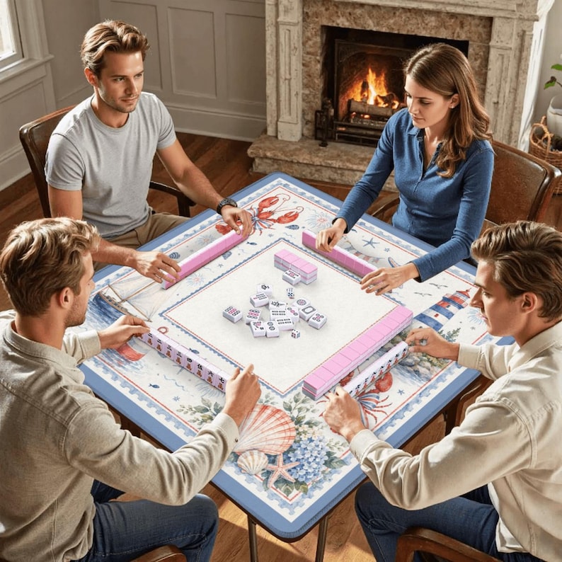 May include: A square Mahjong game table with a nautical theme. The table features a blue border with illustrations of seashells, lobsters, and lighthouses. Four people are playing the game, with pink tile racks and white tiles.