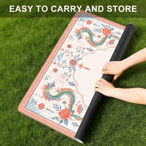 May include: A rectangular mat with a cream-colored surface featuring a repeating pattern of blue and green dragons, red flowers, and lanterns. The mat has a pink border and is being rolled up. The text "EASY TO CARRY AND STORE" is visible at the top.