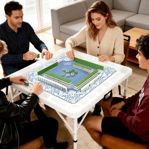 Puede incluir: Cuatro personas jugando al Mahjong alrededor de una mesa plegable blanca. El juego est&aacute; montado sobre una alfombra con estampado azul y blanco. Las fichas verdes y blancas est&aacute;n dispuestas en el tablero. Los jugadores est&aacute;n sentados alrededor de la mesa.