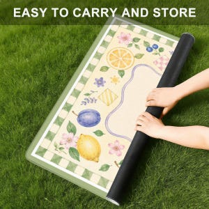 May include: A rectangular mat featuring a cream-colored surface with a green and white checkered border. The design includes illustrations of a yellow lemon, a purple plum, orange slices, blue berries, and pink flowers. The text reads EASY TO CARRY AND STORE.