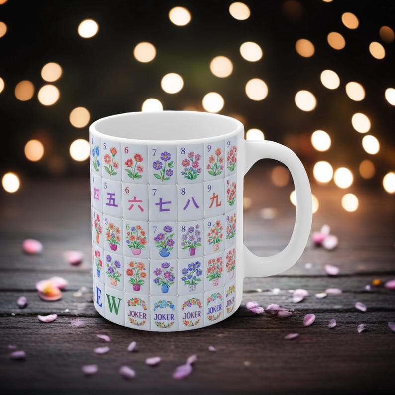 May include: White ceramic mug featuring a design of colorful floral tiles with Chinese characters and numbers. The mug includes the word "Joker" and the letters "EW". The mug has a white handle.