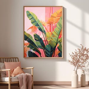 May include: A framed botanical art print featuring large green and yellow banana leaves against a pink and orange background. The artwork is displayed on a wall above a wooden chair with pink cushions and a blanket.