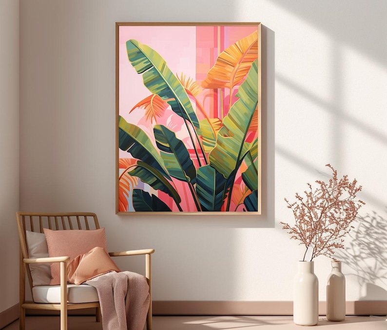 May include: A framed botanical art print featuring large green and yellow banana leaves against a pink and orange background. The artwork is displayed on a wall above a wooden chair with pink cushions and a blanket.