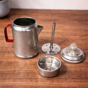 Cafetera miniatura vintage de aluminio con mango rojo y pomo de cristal, juguete para niños.