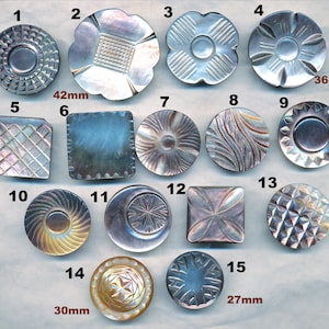 May include: Assortment of 15 iridescent mother of pearl buttons with various designs and sizes. The buttons are numbered 1 through 15. Some buttons are round, some are square, and some are flower-shaped. The buttons range in size from 27mm to 42mm.