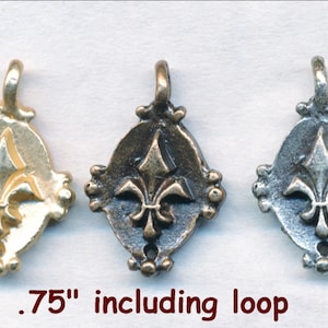 May include: Three metal charms with a fleur-de-lis design. The charms are in gold, bronze, and silver. Each charm is .75 inches including the loop.