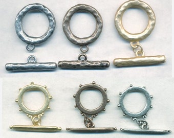 May include: Three sets of silver, gold, and bronze toggle clasps. Each set includes a round ring with a textured surface and a straight bar with a textured surface.