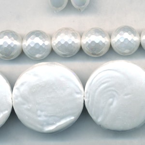 May include: A strand of white round beads with a faceted finish and a strand of white round flat beads.